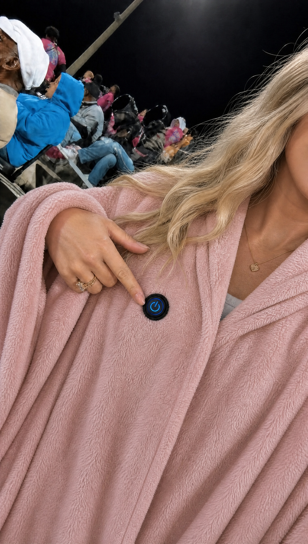 Frau mit der rosa Wärmolo Heizdecke abends im Stadion