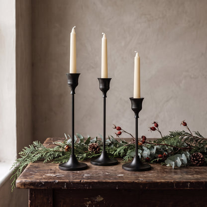 Matte black taper candle holders in three heights on a rustic wooden table