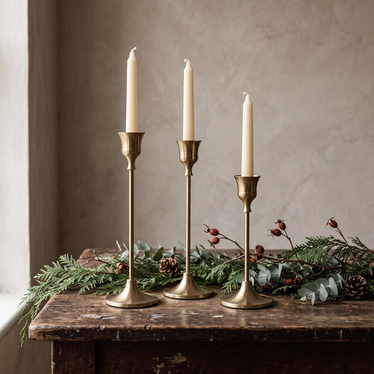 Gold taper candle holders in three heights on a rustic wooden table