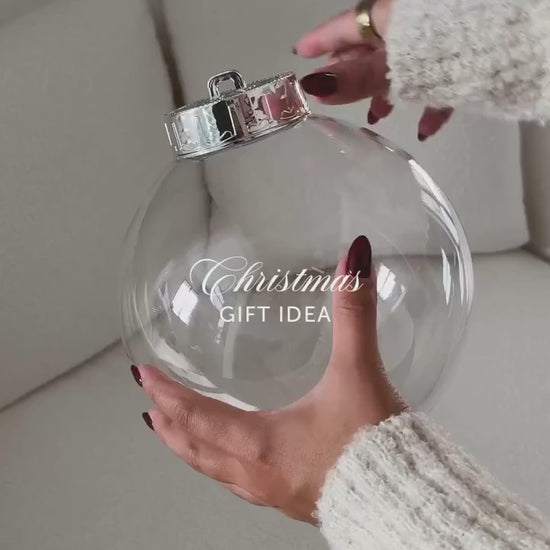 Filling a clear round fillable ornament with gifts